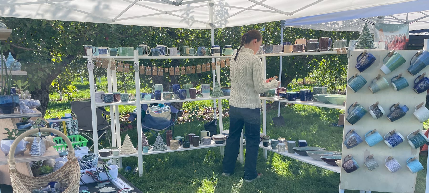 Sheepish Potter market booth with handmade ceramics displayed outdoors.